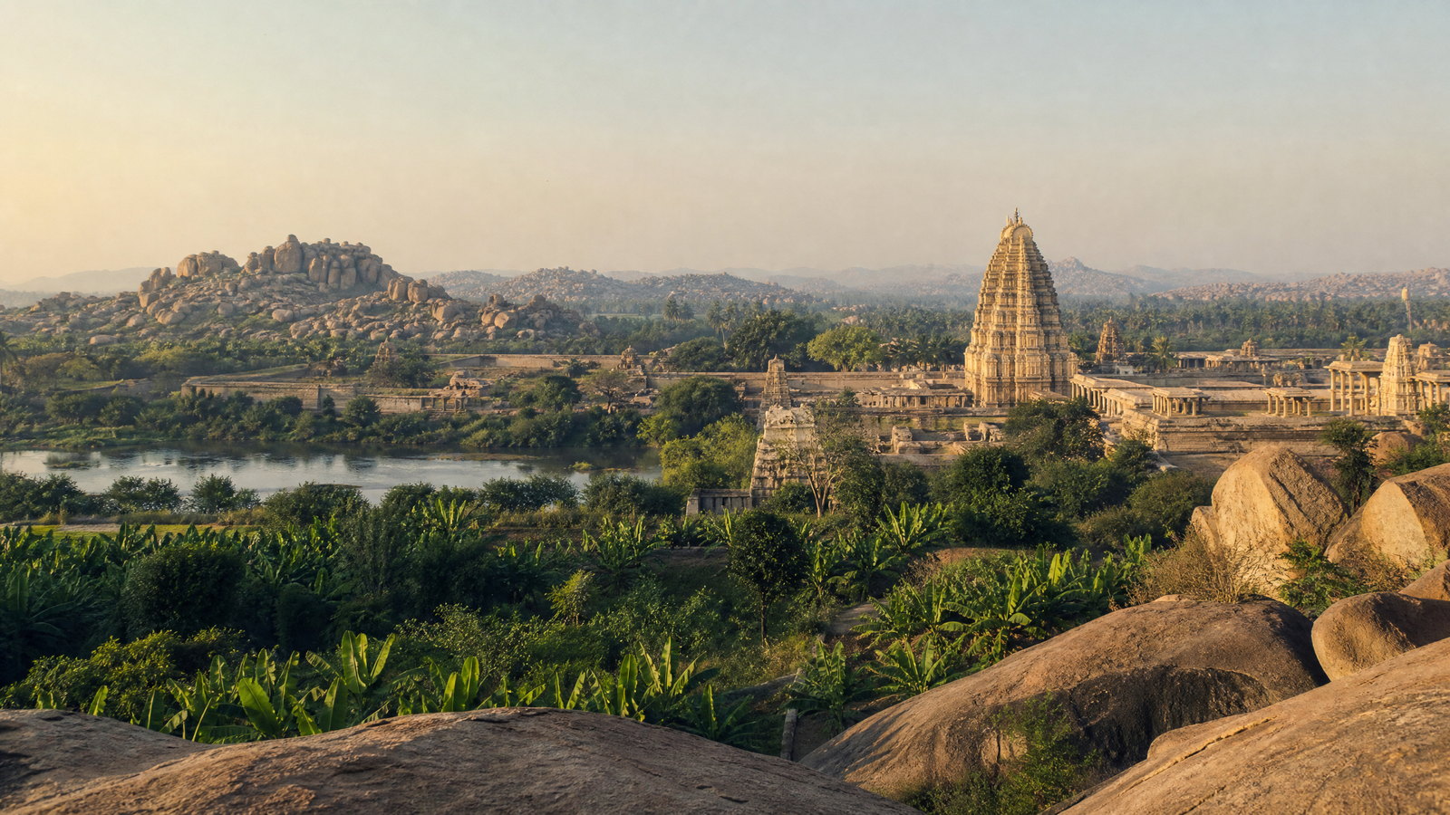 Granite boulders and the Virupaksha Temple tower in Hampi’s broad Tungabhadra valley at first light.