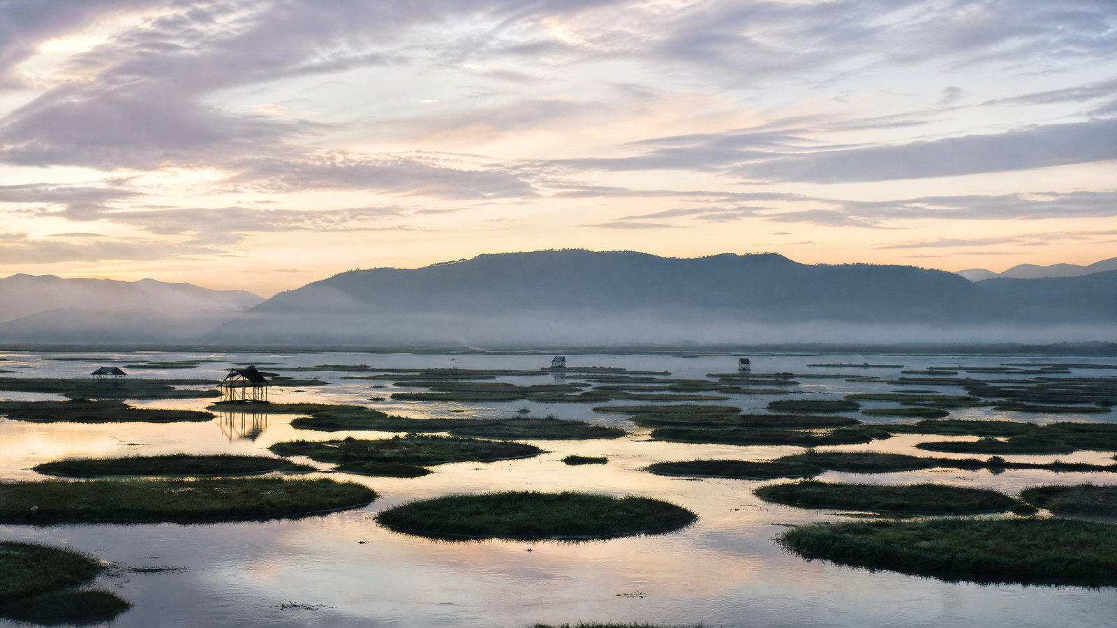 Morning light over Loktak Lake’s floating phumdi meadows and low forested hills in Manipur