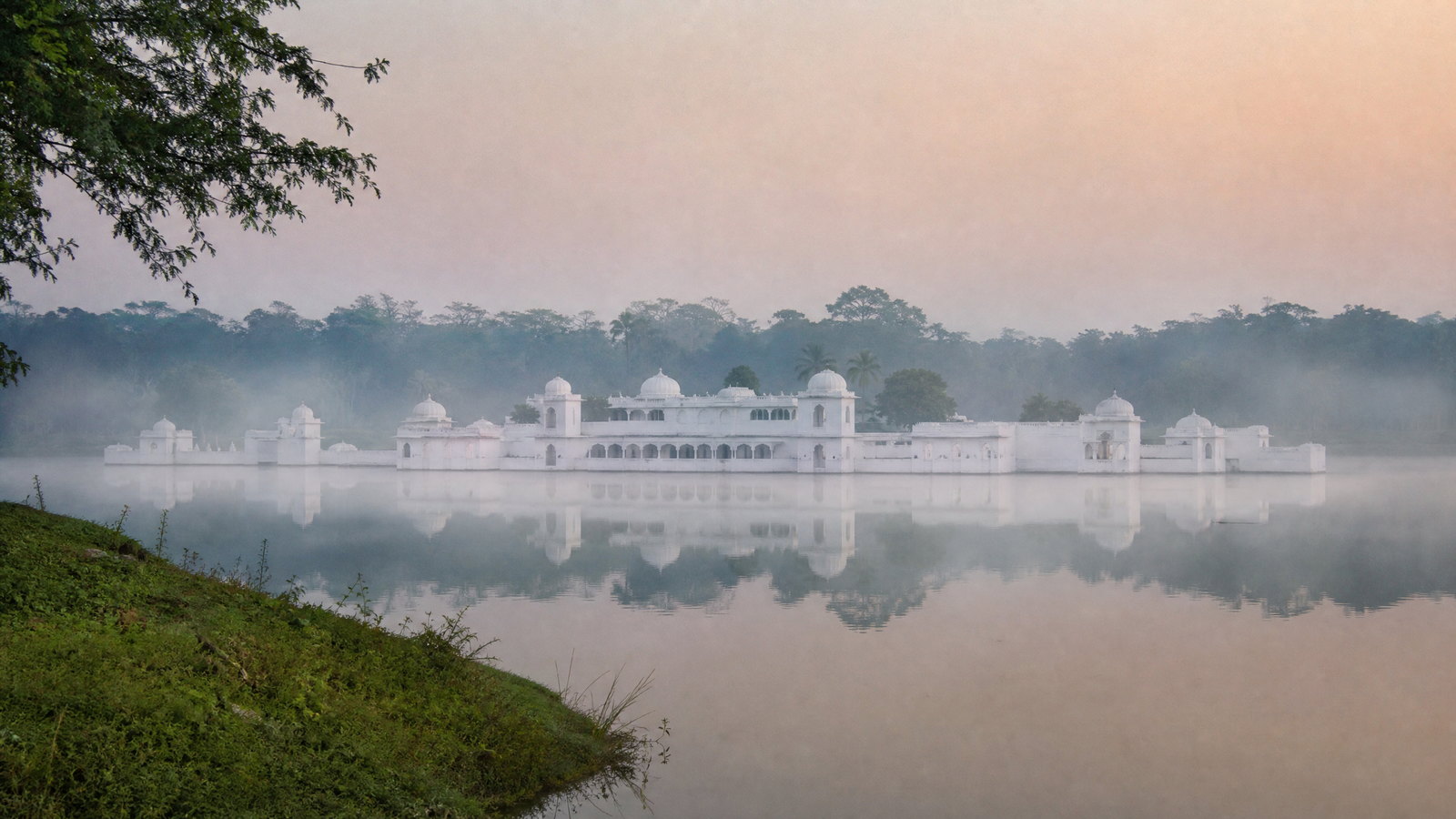 White Neermahal water palace reflected in the calm waters of Rudrasagar Lake at first light, Tripura