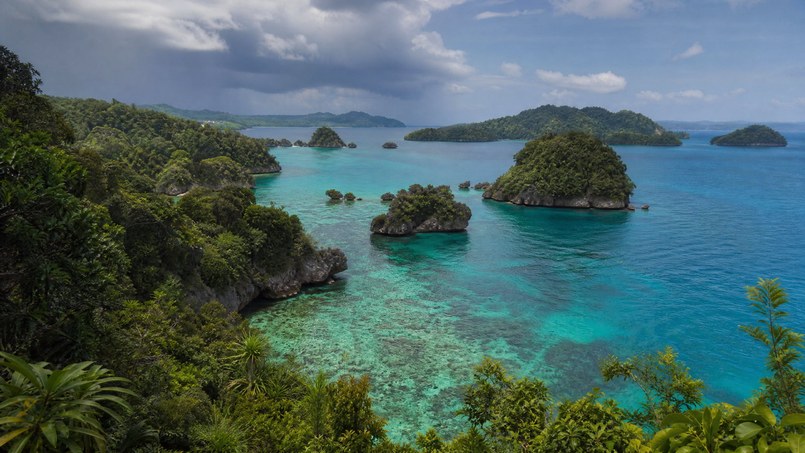 Aerial view of a pale sandbar joining two forested Andaman islands in clear turquoise water.