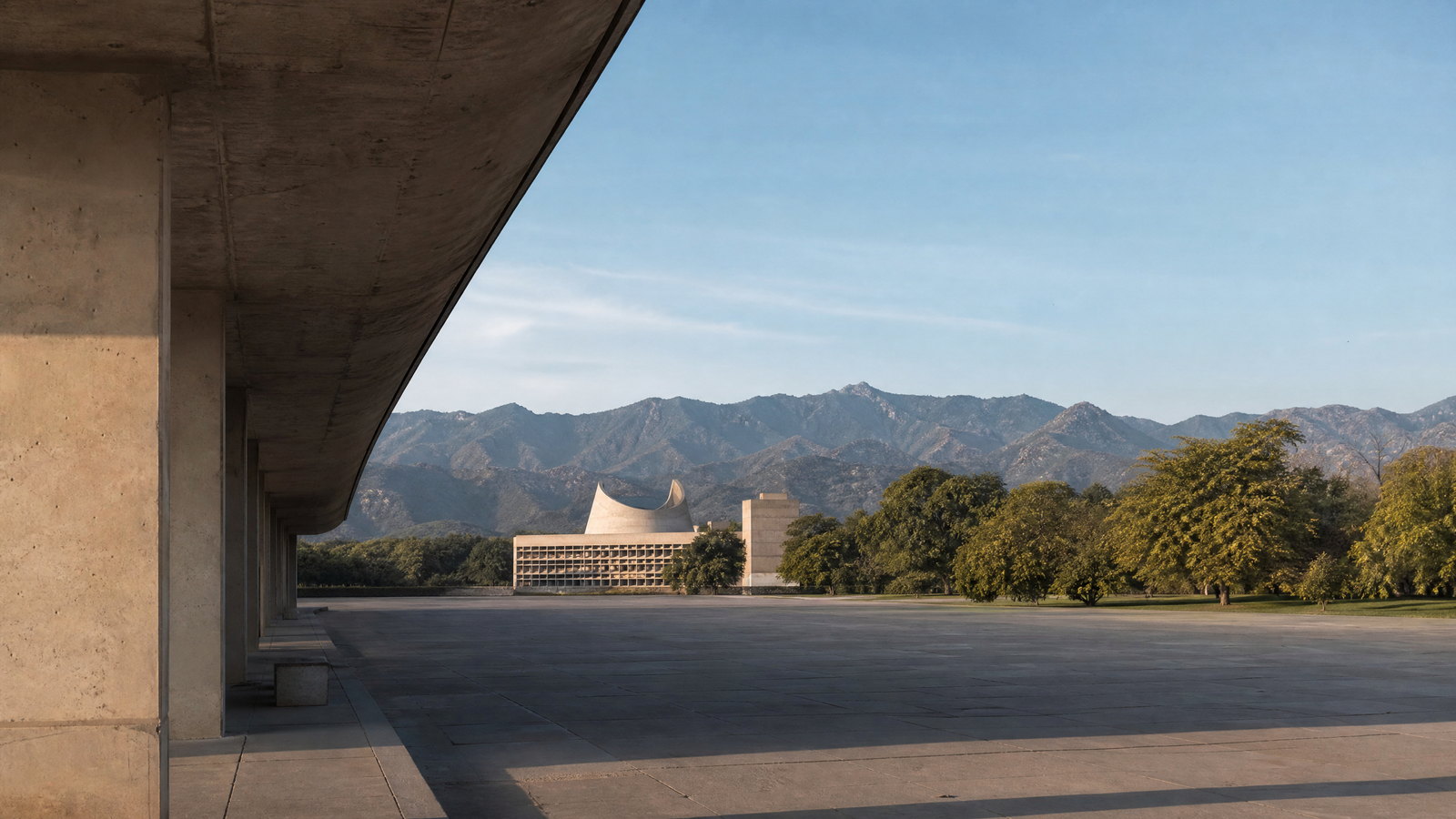 The Open Hand monument and geometric concrete forms of Chandigarh’s Capitol Complex framed by the Shivalik foothills under clear winter light.