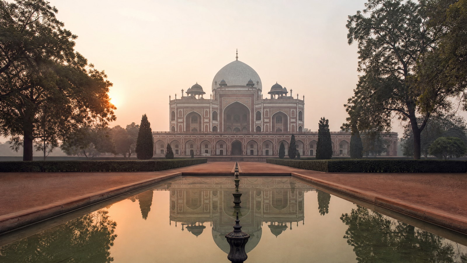 Dawn light on the red sandstone arcades and domes of Humayun’s Tomb garden in Delhi.