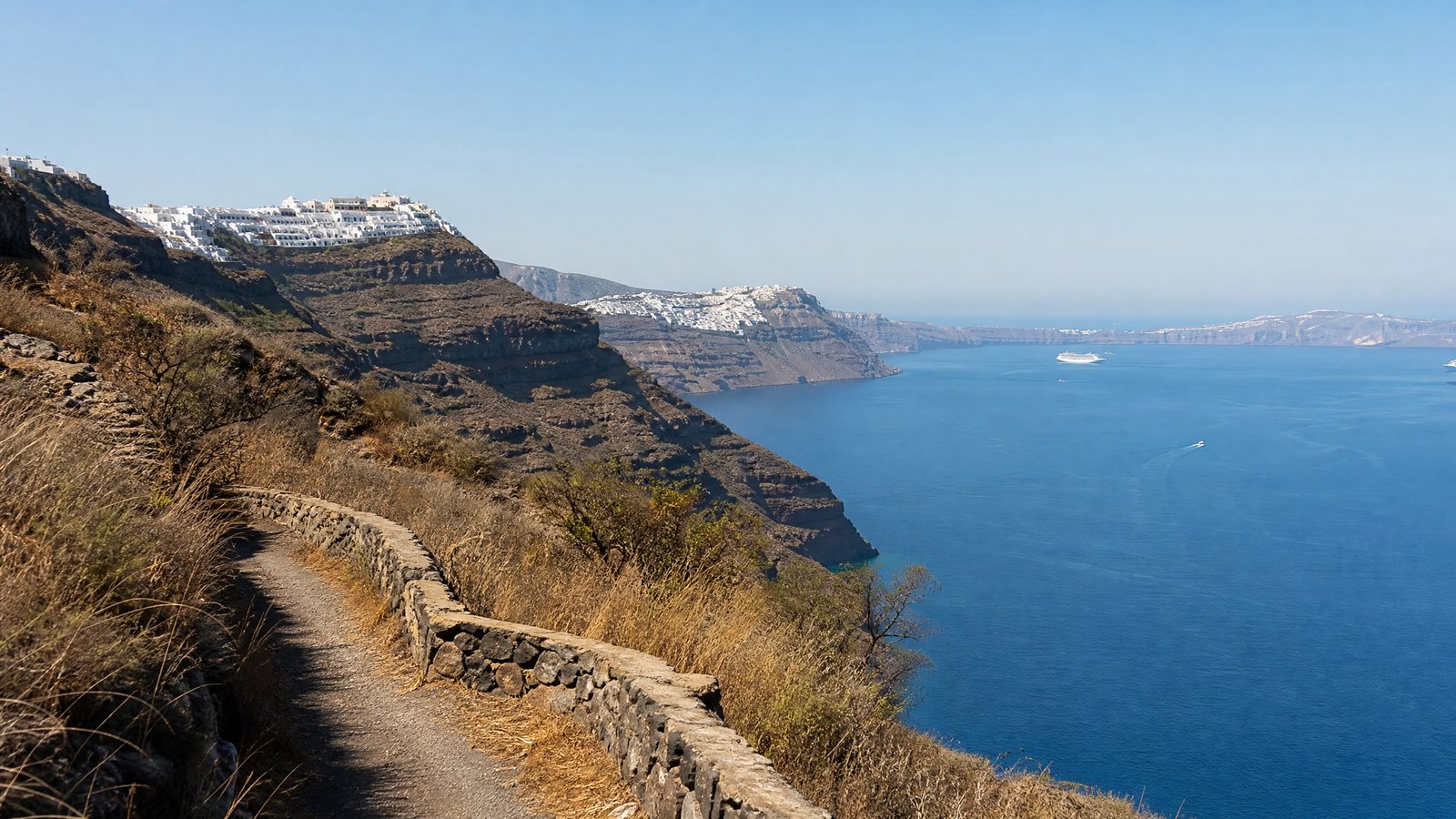 Santorini's volcanic caldera seen from a quiet inland footpath in clear morning light
